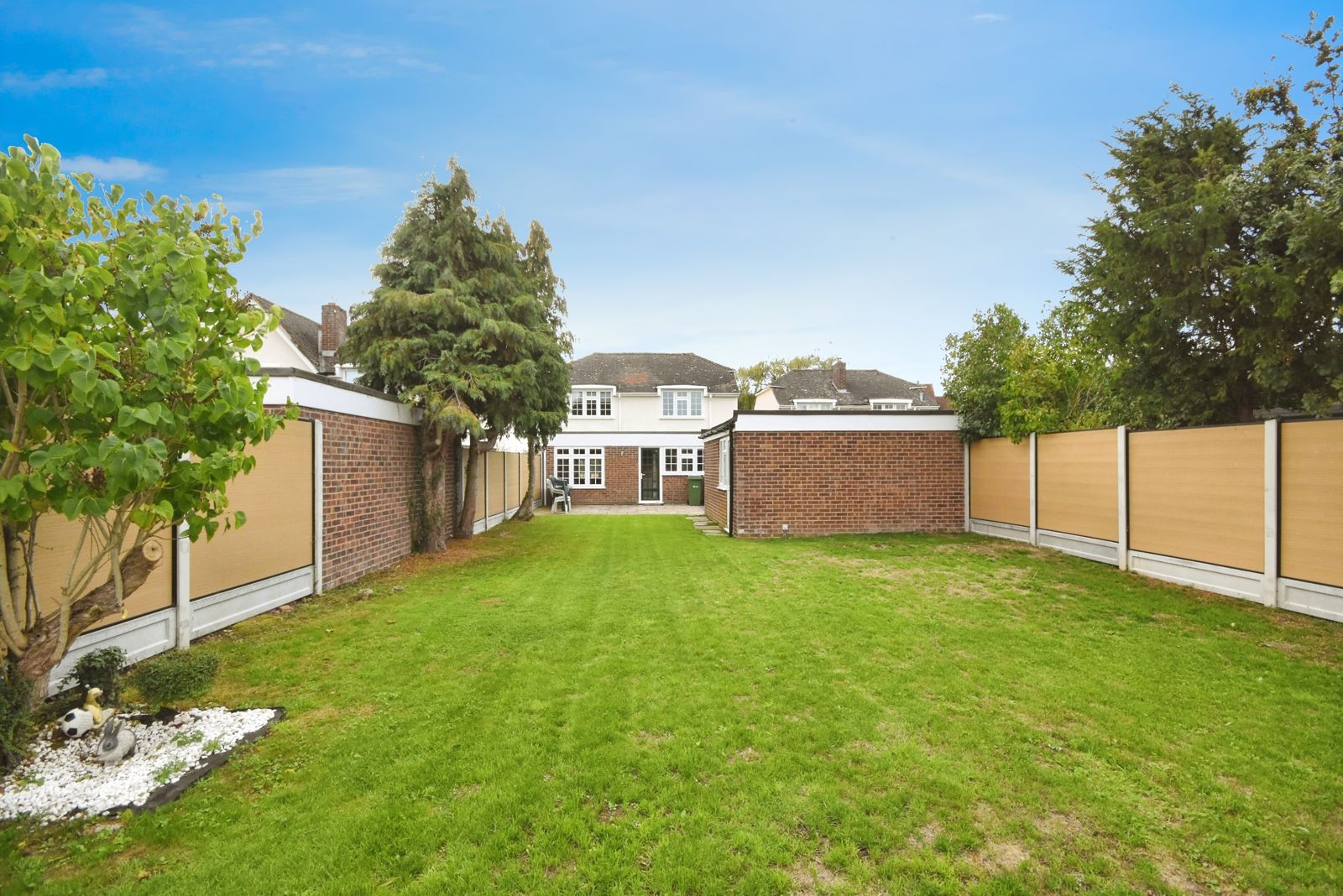 Long lawned rear garden looking back at the house, fully fenced on both sides