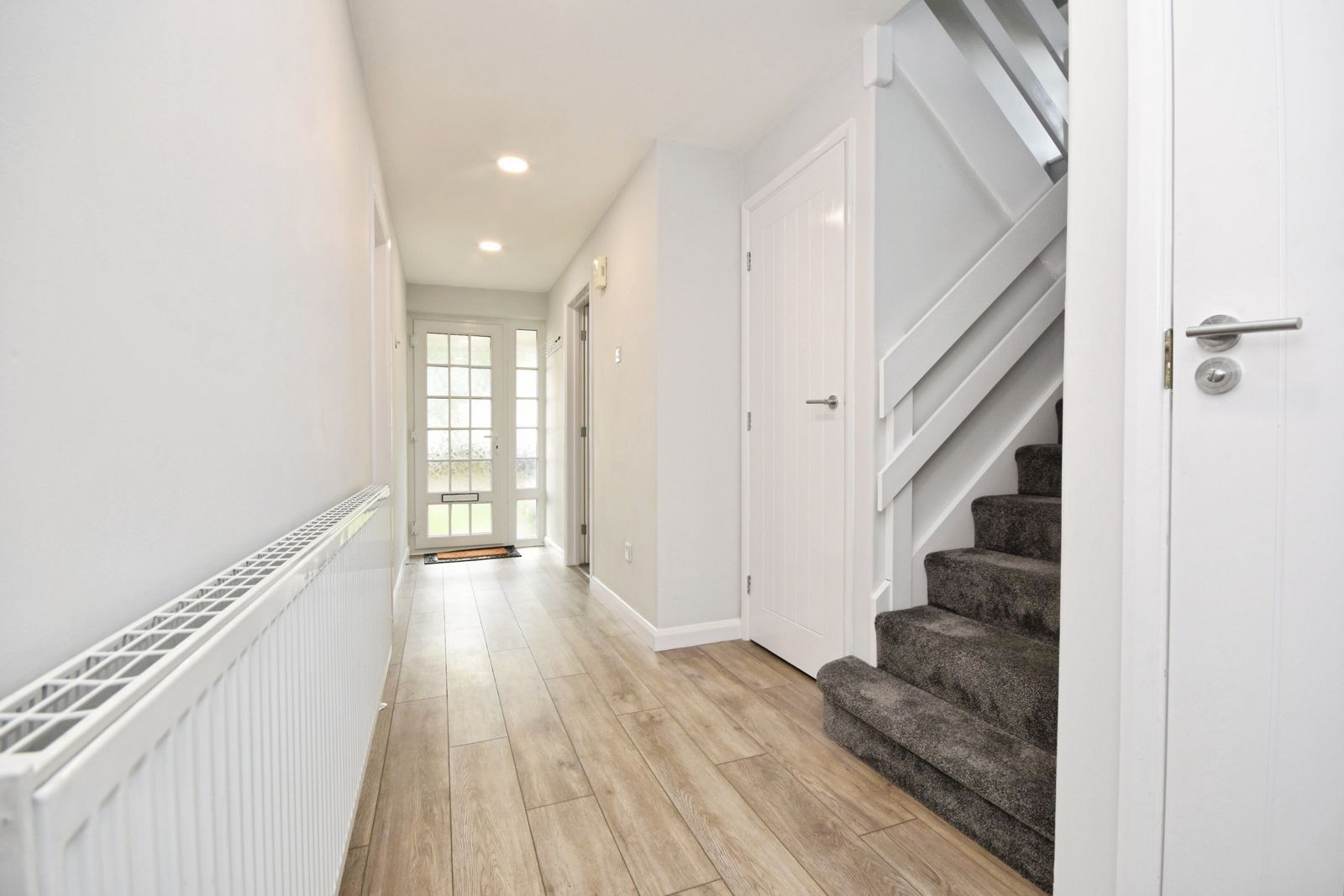 Bright hallway with oak-effect floor and carpeted staircase