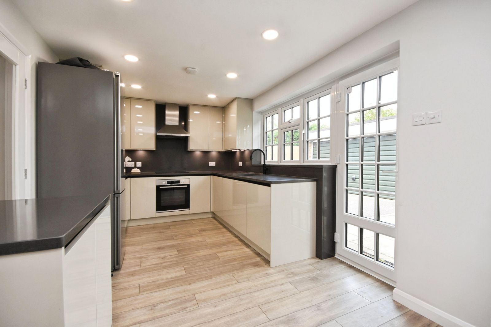 Chef's kitchen with gloss cabinetry, dark worktops and cottage windows