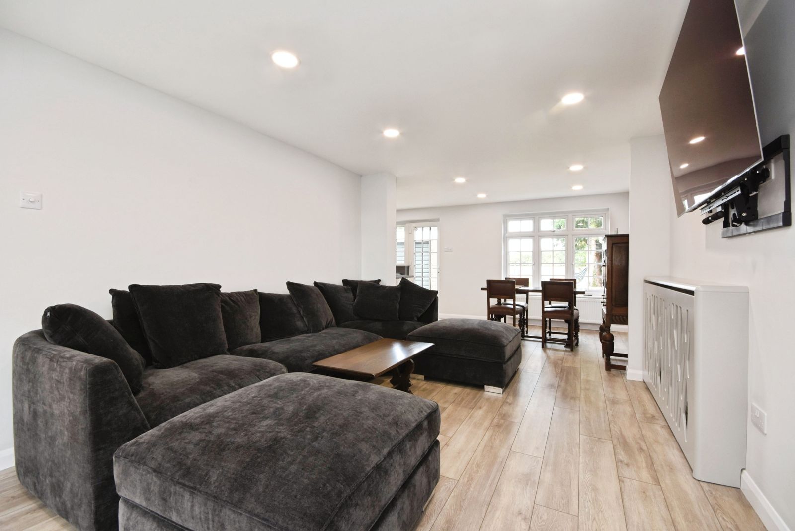 Lounge with corner sofa, wall-mounted TV and wood-effect flooring